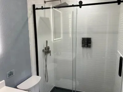 a bathroom with a glass shower with a toilet at Signature Suite in Orlando