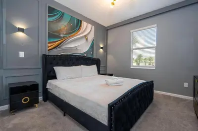 a bedroom with a bed with a painting on the wall at Stunning Mansion 15 ensuites in Kissimmee