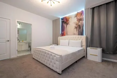 a bedroom with a white bed with a painting on the wall at Stunning Mansion 15 ensuites in Kissimmee