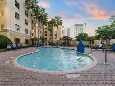 a swimming pool with blue lounge chairs and buildings at SkySuite 5min to Universal Park in Orlando