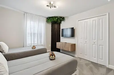 a white bedroom with a bed and a tv at Casa Disney | Piscina Privativa no Storey Lake in Kissimmee