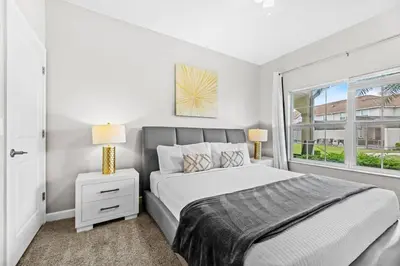 a white bedroom with a bed and a window at Casa Familiar no Storey Lake c/ Piscina in Kissimmee