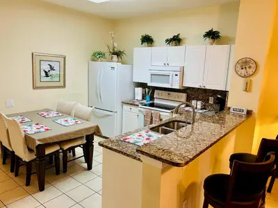 a kitchen with a table and a kitchen with white cabinets at The Orlando Hideaway Family Townhome Steps from Disney 3BR 3BA in Kissimmee