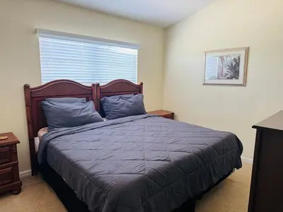 a bedroom with a bed with blue pillows and a window at The Orlando Hideaway Family Townhome Steps from Disney 3BR 3BA in Kissimmee