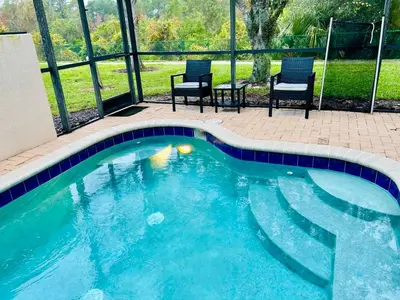 a swimming pool with two chairs and a table at The Orlando Hideaway Family Townhome Steps from Disney 3BR 3BA in Kissimmee