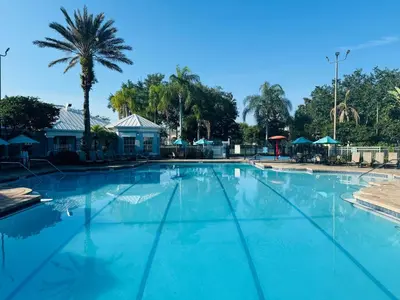 a large blue swimming pool with a palm tree at The Orlando Hideaway Family Townhome Steps from Disney 3BR 3BA in Kissimmee
