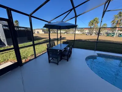 a patio with a table with an umbrella and a pool at Casablanca Villa home in Kissimmee