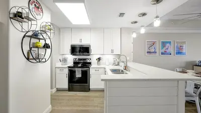 a kitchen with white cabinets and a black stove at Wands & Wishes | Luxury Condo Minutes from Disney in Orlando