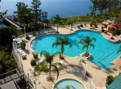 a large swimming pool with palm trees and the ocean at Wands & Wishes | Luxury Condo Minutes from Disney in Orlando