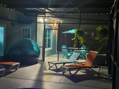 a patio with chairs and a table with an umbrella at Charming, beautiful house closer to Disney World in Orlando