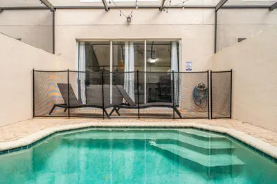 a swimming pool with two chairs and a balcony at Magical Stay Near Disney I Pool and Resort Access in Kissimmee