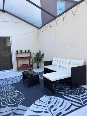 a patio with a couch and a table on a rug at Toy Story Getaway Retreat in Kissimmee