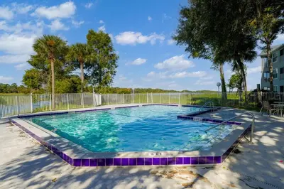 a large swimming pool with blue water and purple tiles at Spacious 2BR Condo Near Disney with Pool & Basketball in Kissimmee
