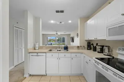 a kitchen with white cabinets and a sink at Spacious 2BR Condo Near Disney with Pool & Basketball in Kissimmee