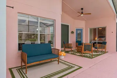 a pink house with a blue couch on a porch at [Popular Illusion Home] •Waterfront Private Pool in Kissimmee
