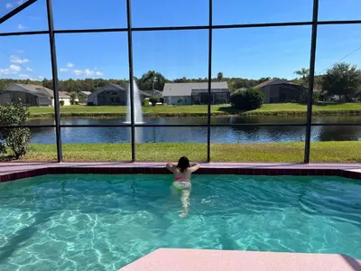a woman in a swimming pool looking out of a window at [Popular Illusion Home] •Waterfront Private Pool in Kissimmee