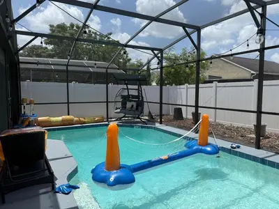 a large swimming pool with a canopy and an inflatable at 3 bedroom home with private pool in Orlando