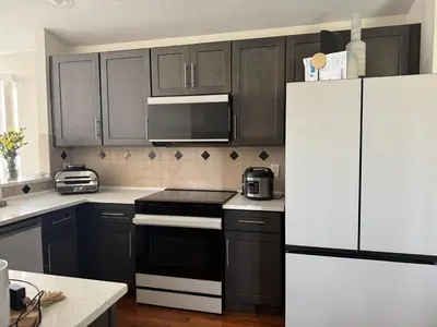 a kitchen with black cabinets and a white refrigerator at 3 bedroom home with private pool in Orlando