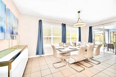 a dining room with blue curtains and a table and chairs at Bella Vida House with Pool and Games - Near Disney! in Kissimmee