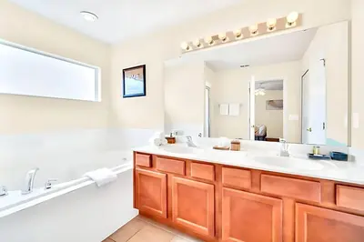 a bathroom with two sinks and a large mirror at Bella Vida House with Pool and Games - Near Disney! in Kissimmee