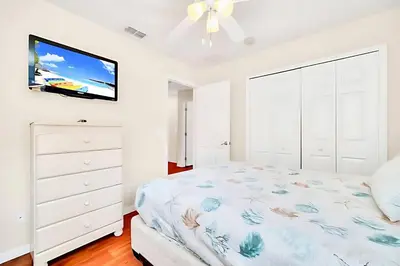 a white bedroom with a bed and a tv at Bella Vida House with Pool and Games - Near Disney! in Kissimmee