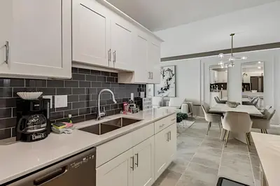 a kitchen with white cabinets and a sink and a table at Condo Luxo 3 Quartos | Storey Lake Resort in Kissimmee