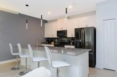 a kitchen with a counter with chairs and a refrigerator at Townhouse Moderna 4Q c/ Piscina /10 Min da Disney! in Kissimmee