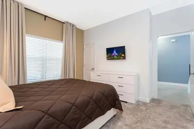 a bedroom with a bed and a tv on the wall at Townhouse Moderna 4Q c/ Piscina /10 Min da Disney! in Kissimmee