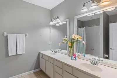 a bathroom with a sink and a mirror and flowers at Elegante Casa 3 Quartos no Vista Cay in Orlando