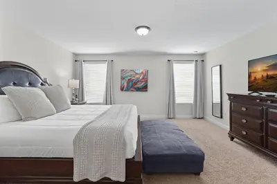 a bedroom with a bed and a dresser and windows at Vila 6 Quartos Storey Lake com Piscina & Spa in Kissimmee