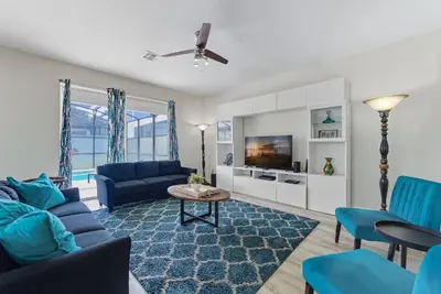 a living room with blue couches and a tv at Vila 6 Quartos Storey Lake com Piscina & Spa in Kissimmee