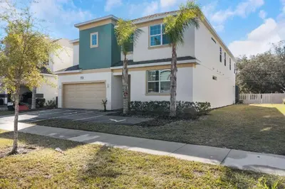 a house with palm trees in front of it at Cozy Rooms In An Elegant House in Kissimmee