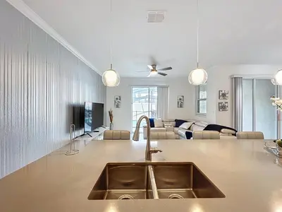a kitchen with a sink and a living room at Luxury Pool Home Near Disney Resort Access in Kissimmee