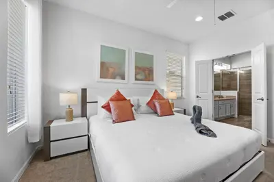 a white bedroom with a large bed with orange pillows at Pool 4BR Resort Home Near Disney in Kissimmee