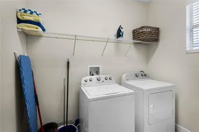 a laundry room with two washing machines and a shelf at Luxury Pool Home Near Disney Resort Amenities in Kissimmee