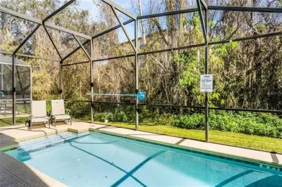 a swimming pool with two chairs and a glass house at Luxury Pool Home Near Disney Resort Amenities in Kissimmee