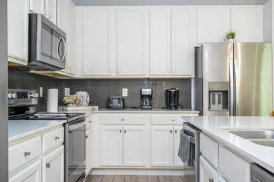 a kitchen with white cabinets and stainless steel appliances at 12BR Home w Game Room Movie Theater in Kissimmee