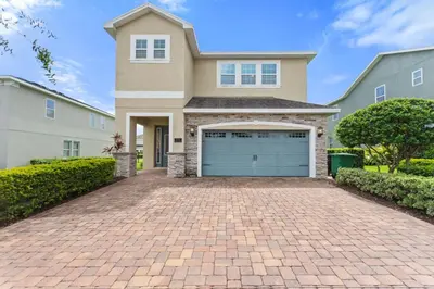 a house with a brick driveway in front of a garage at Sunset Games Retreat at Reunion Resort villa in Orlando