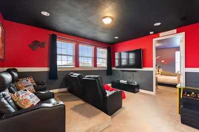 a living room with red walls and black leather chairs at Sunset Games Retreat at Reunion Resort villa in Orlando