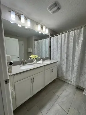 a bathroom with two sinks and a large mirror at 4BR-3BA Townhouse with Private Pool in Storey Lake in Kissimmee