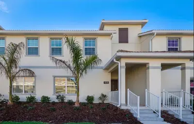 a house with a palm tree in front of it at 4BR-3BA Townhouse with Private Pool in Storey Lake in Kissimmee