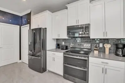 a kitchen with white cabinets and stainless steel appliances at Last Minute Disney Private Pool Hot Tub Game Room Themed Bedrooms. Book Now SLR551 in Kissimmee