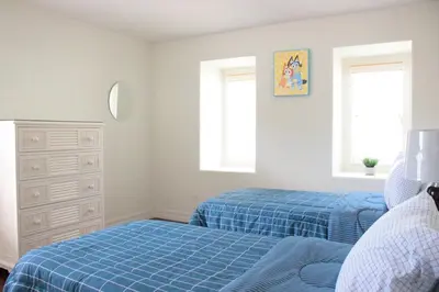 a bedroom with two beds and a dresser and two windows at Relaxing Villa near the Parks! in Orlando