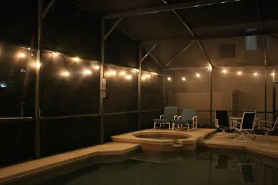 a room with a swimming pool and chairs and lights at Relaxing Villa near the Parks! in Orlando