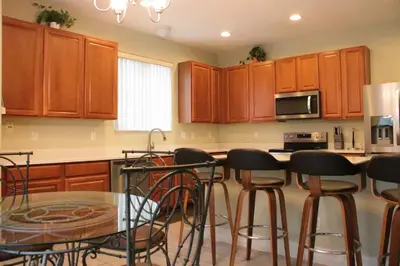 a kitchen with wooden cabinets and a table with bar stools at Relaxing Villa near the Parks! in Orlando