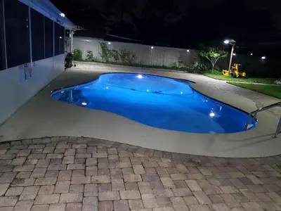 a blue swimming pool in a yard at night at Paradise Apartment in Orlando