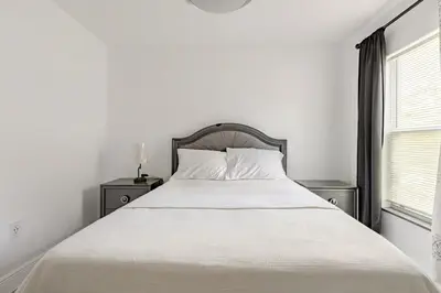 a white bed in a white bedroom with a window at Paradise Apartment in Orlando