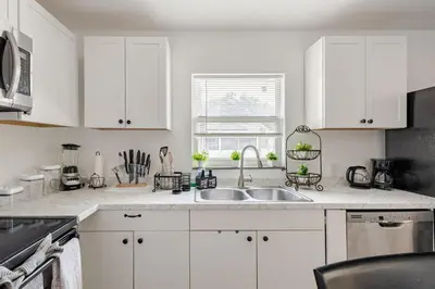 a kitchen with white cabinets and a sink at Paradise Apartment in Orlando