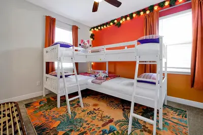 two bunk beds in a room with red walls at Family Escape | Moana Vibes | Pool + Games in Orlando