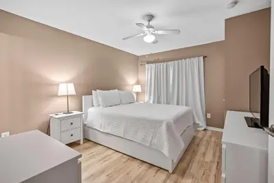 a bedroom with a white bed and a ceiling fan at Cozy Themed 04 bedrooms - Close to Disney in Kissimmee